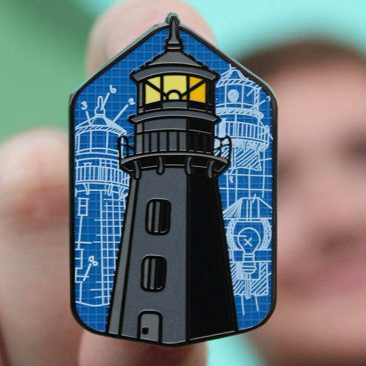 man holding enamel pin of garden key lighthouse