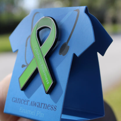 Green ribbon cancer awareness enamel pin on a blue card