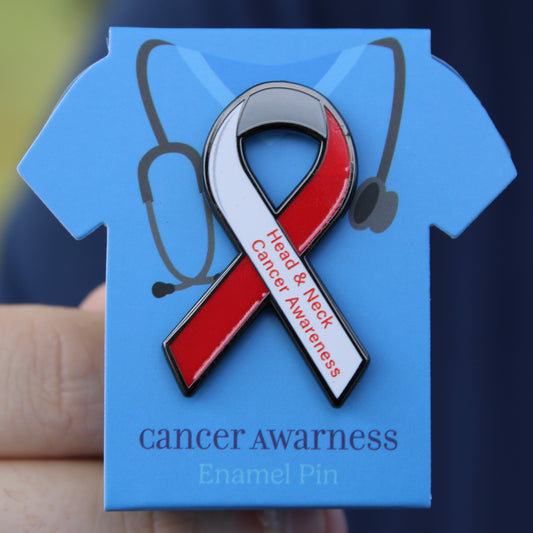 Red and white head and neck cancer awareness ribbon enamel pin on backing card with stethoscope, labeled 'cancer awareness enamel pin'.