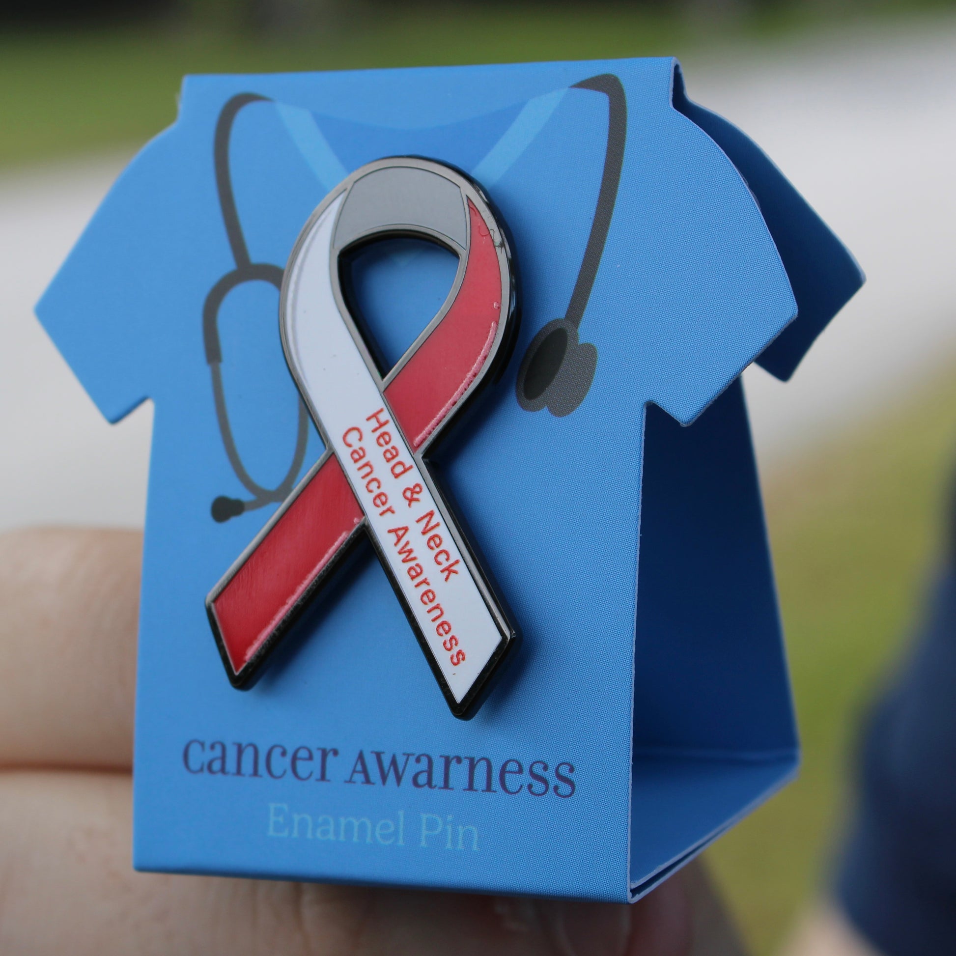 Red and white cancer awareness ribbon enamel pin on a blue card with 'cancer awareness' text.