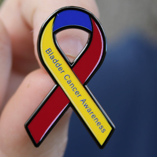 Bladder cancer awareness ribbon pin held in a hand with a blurred background