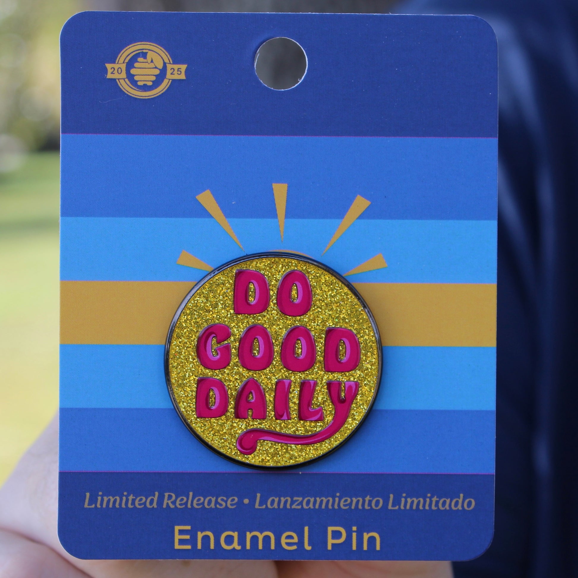 yellow glitter Enamel pin with 'Do Good Daily' text on a blue card