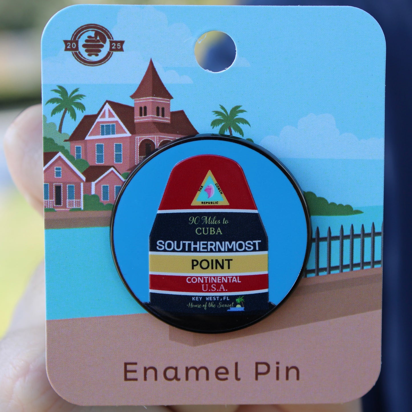 Enamel pin with Southernmost Point design on a card with beach scene