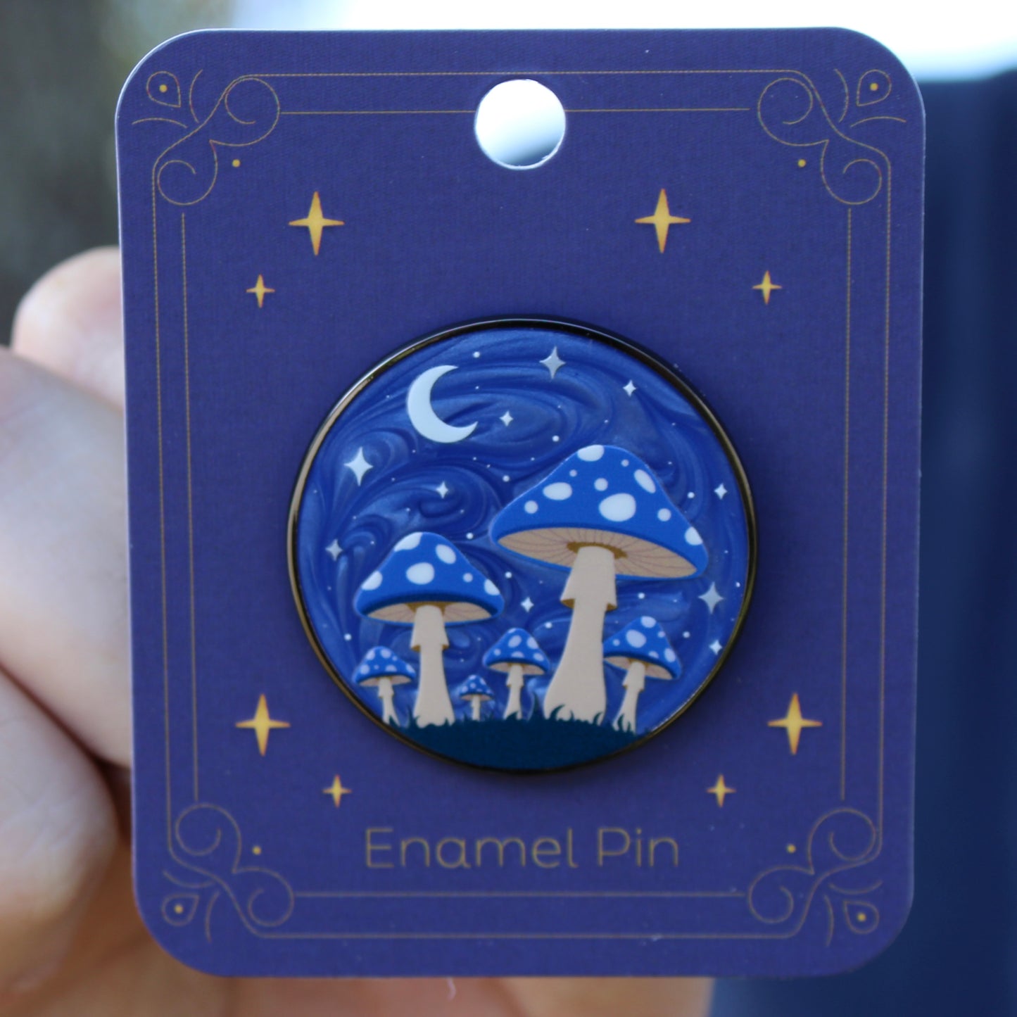 Blue enamel pin with mushroom forest design on a matching card