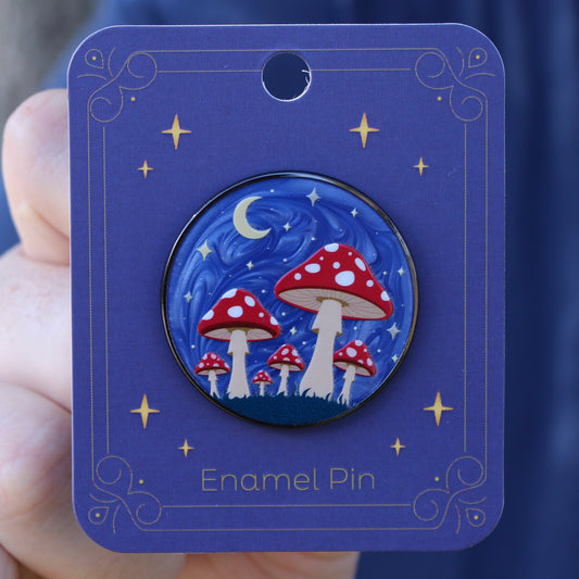 Enamel pin with red mushroom forest design on a blue card