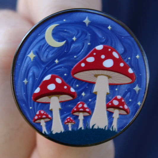 Round blue badge with red and white mushrooms on a starry night design
