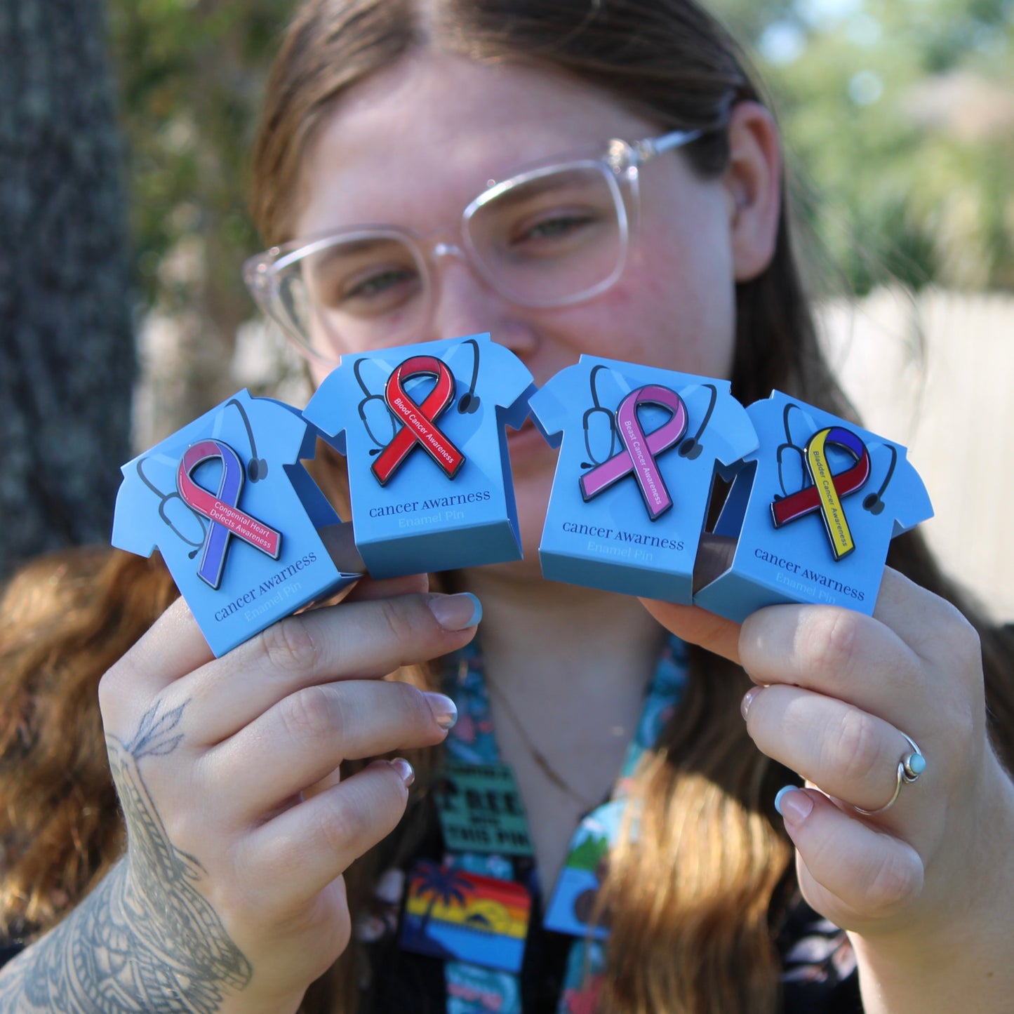 person holding 4 cancer awareness pins with scrub displays