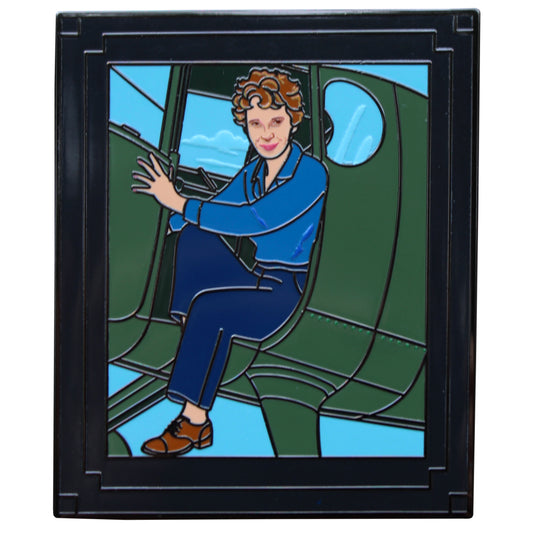 enamel pin of a framed photo of amelia earhart smiling and sitting half out of a green plane
