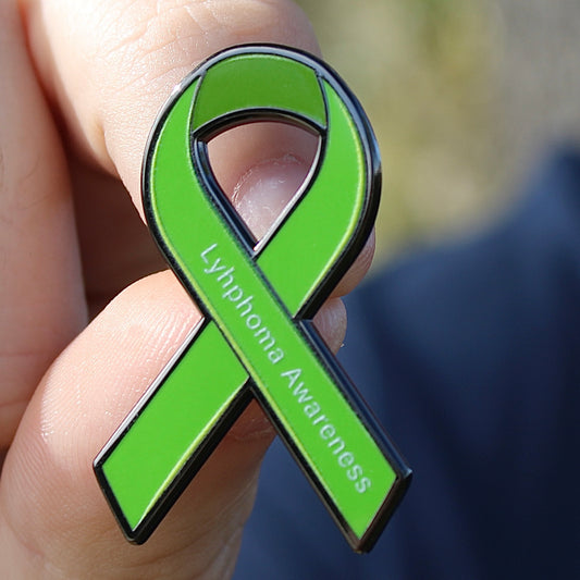 Green ribbon with 'Lymphoma Awareness' text held between fingers against a blurred background